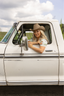 Woman wearing a cowboy hat sitting in a white truck with a scenic background