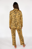 Woman wearing a luxury tiger stripe pajama set with bows incorporated into the stripes on a white background