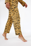 Woman wearing a luxury tiger stripe pajama set with bows incorporated into the stripes on a white background