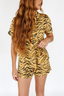 Woman wearing a luxury tiger print pajama set with bows incorporated into the stripes on a white background