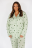 Woman wearing a green gingham pajama set with alpine trees on a white background
