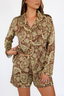 Woman wearing a luxury pajama set with brown and lime punch paisley pattern on a white background