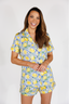 Woman wearing a colorful pajama set with lemons and blue patterns on a white background