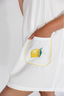White garment with a lemon embroidered on a pocket against a white background