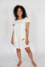 Woman wearing a white nightgown with yellow accents on a plain background