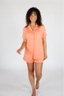 Woman wearing a peach-colored pajama set on a white background