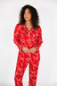 Woman wearing a red pajama set with white bow pattern on a white background