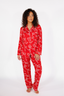 Woman wearing a red pajama set with white bow pattern on a white background