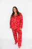 Woman wearing a red pajama set with white bow pattern on a white background