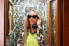 Person wearing sunglasses and a luxury leopard print pajama set in a patterned phone booth.