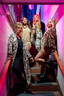 Four women in leopard print luxury pajamas posing on a staircase with pink walls.