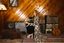Woman in a leopard print luxury long robe standing in a room with musical equipment and wooden walls.