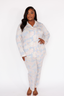 Woman wearing a light blue pajama set with blue and pink flying pigs pattern on a white background