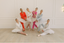 Dancers in colorful outfits posing in a studio with a white wall background