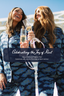 Two women in blue pajama sets holding champagne glasses with a text overlay about National Pajama Day.