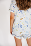 Person wearing a white pajama set with colorful patterns on a plain background