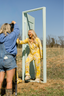 Mallory Ervin standing in a doorframe in a field laughing and wearing a yellow modal pajama set.