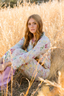 A woman sitting in a field wearing a modal pajama set in a print with butterflies and flowers.