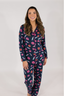 A woman wearing a navy long sleeve pajama top with a lipstick print design, paired with matching pants, standing against a white background.