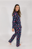 A woman wearing a navy long sleeve pajama top with a lipstick print design, paired with matching pants, standing against a white background.