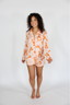 Woman wearing a patterned shirt and shorts on a white background