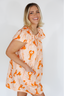 Woman wearing an orange and white patterned dress on a plain background