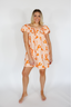 Woman wearing an orange and white patterned dress on a white background