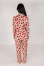 A woman wearing a long sleeve and pant pajama set with a red rose pattern on a white background.