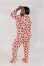 A woman wearing a long sleeve and pant pajama set with a red rose pattern on a white background.