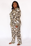 Woman wearing a luxury leopard print pajama set with lime punch colored piping on a white background