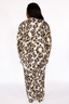 Woman wearing a luxury leopard print pajama set with lime punch colored piping on a white background