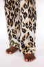 Woman wearing a luxury leopard print pajama set with lime punch colored piping on a white background