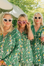 Three women in matching green leaf-patterned pajamas with sunglasses, standing outdoors.