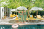 Three women in matching green pajama sets standing by a pool with yellow lounge chairs and white umbrellas.