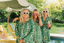 Three women in matching green floral robes by a poolside.