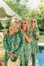 Three women in matching green floral pajamas standing by a pool with trees in the background.