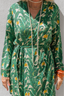 Green patterned robe with long sleeves and a belt, worn by a person.