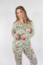 A woman wearing a long sleeve and pant pajama set with a floral pattern in pink and green colors.
