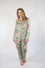 A woman wearing a long sleeve and pant pajama set with a floral pattern in pink and green colors.