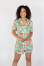 A woman wearing a short sleeve and short pajama set with a peony blossom print.