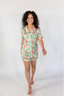 A woman wearing a short sleeve and short pajama set with a peony blossom print.