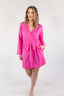 A woman wearing a pink short robe with a tie waist, made from a soft and comfortable fabric.