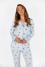 Woman wearing a light blue pajama set with red santa patterns on a white background