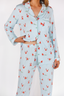 Woman wearing light blue pajamas with red santa patterns on a white background