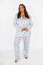 Woman wearing light blue pajamas with red santa patterns on a white background