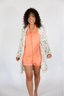 Woman wearing a peach outfit with a floral cover-up against a white background