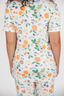 Person wearing a pajama set with a colorful fruit and floral pattern on a white background