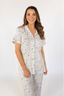 A woman wearing a short sleeve and cropped pant pajama set with a tea set pattern.