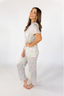 A woman wearing a short sleeve and cropped pant pajama set with a tea set pattern.