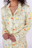 A woman smiling, wearing a green sleep dress with a floral wildflowers pattern.